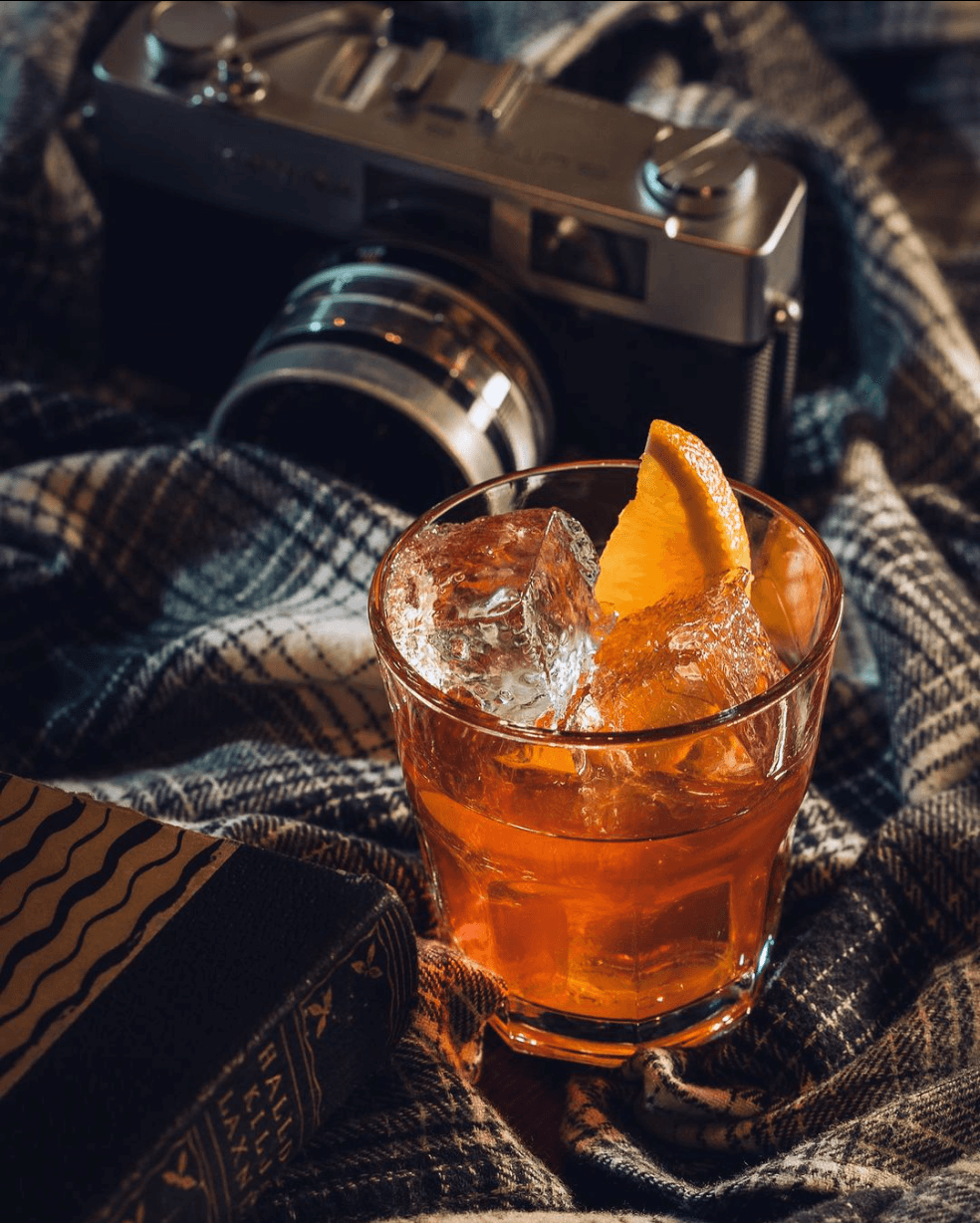 Kokteill við hlið myndavélar og bókar